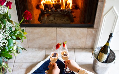 Resort guests spending a romantic weekend at Silverado resort with a bottle of wine in front of the fireplace