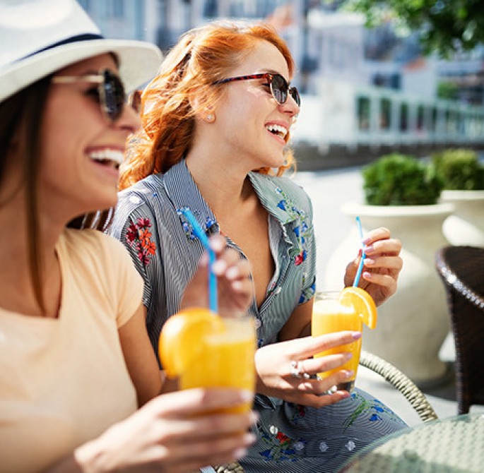 two women drinking orange juice at the street