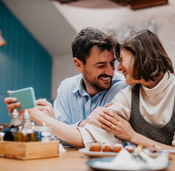 couple smiling at each other eating breakfast
