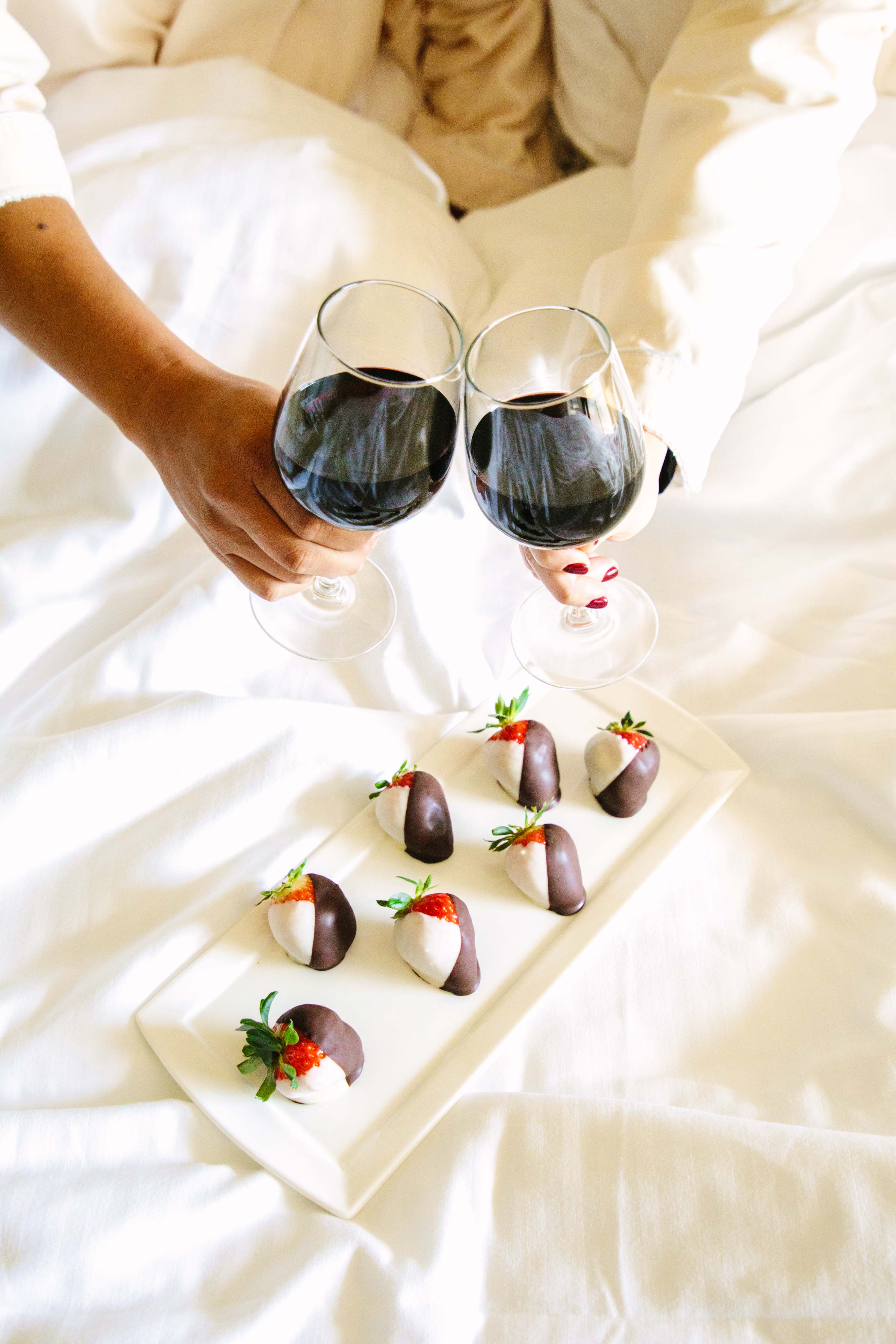 a couple enjoying chocolate dipped strawberries and red wine 