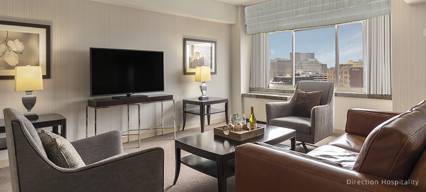inside guest room at the stamford chairs leather couch and tv