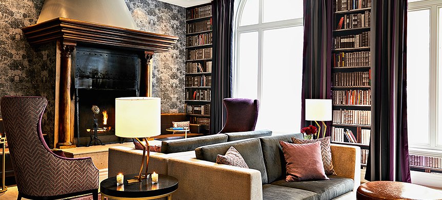 Living space with black marble fireplace and library next to windows