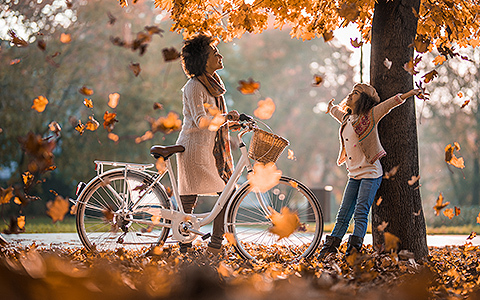 woman and daughter playing in fall leaves