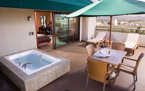 Outdoor Terrace Spa room sliding door leads out to ultra-spacious private balcony with jetted tub, chaise lounge and bistro dining table with umbrella. 