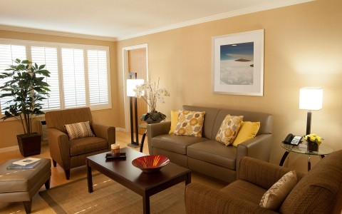 Double Suite room with seating area contains couch, coffee table, several single chairs, lamp adjacent to window