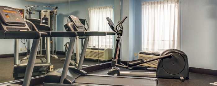 Fitness room with cardio machines in front of mirror