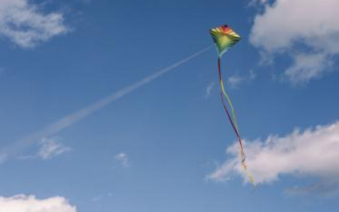 Colorful Kite Flying in a blue sky with white fluffy clouds