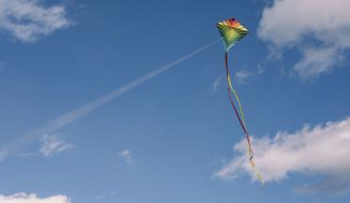 Colorful Kite Flying in a blue sky with white fluffy clouds