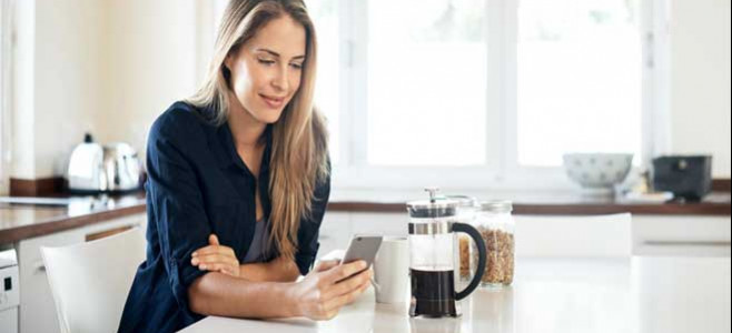 Young woman on her phone while enjoying a cup of coffee