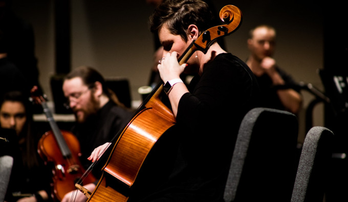 concert cellist wearing black while playing in a symphony