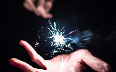 magicians hands creating a spark with a wand between 2 hands