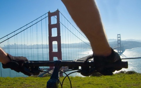 person on bike atop a cliff in front of golden gate bridge