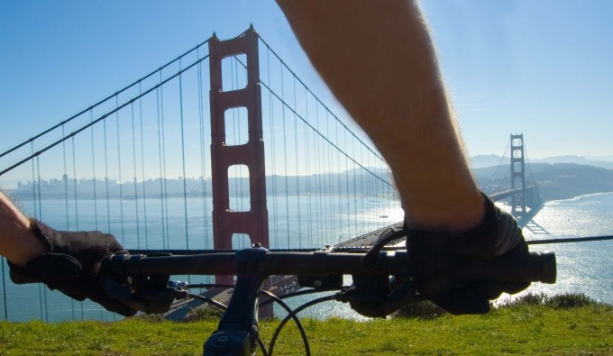 person on bike atop a cliff in front of golden gate bridge
