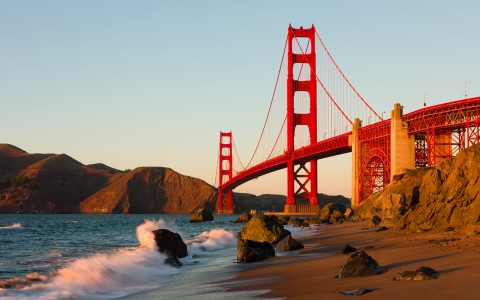 wave crashing on shore under the golden gate bridge
