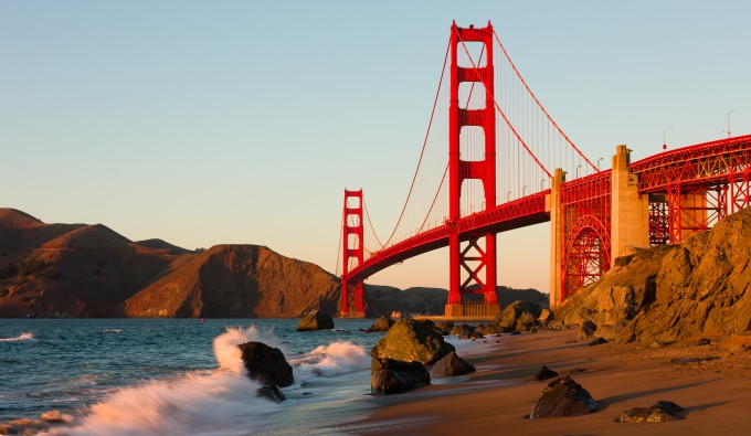 wave crashing on shore under the golden gate bridge