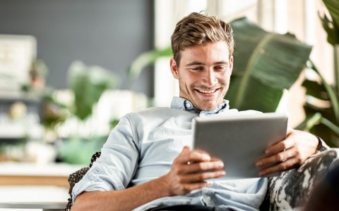 Smiling man watching something in his tablet 