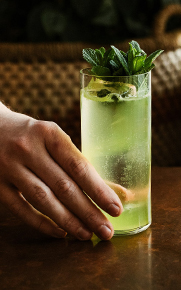 a hand holding a green cocktail 
