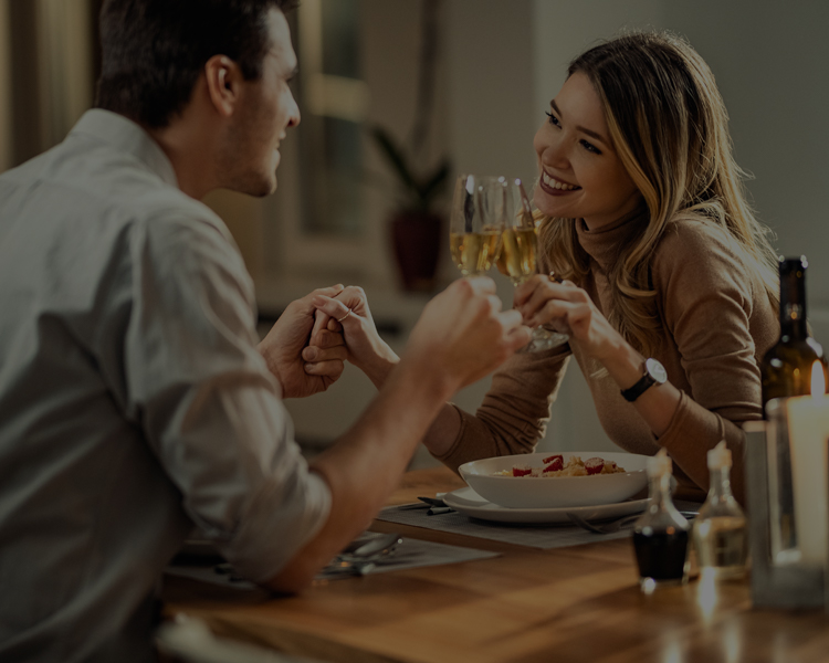 man and woman hold hands while enjoying glass of white wine