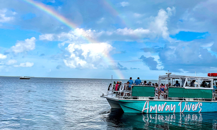amoray boat in the ocean with a rainbow behind 