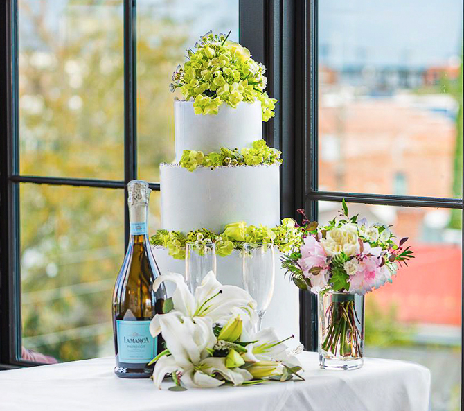 a wedding cake with green decorations and champagne glasses in front of the cake