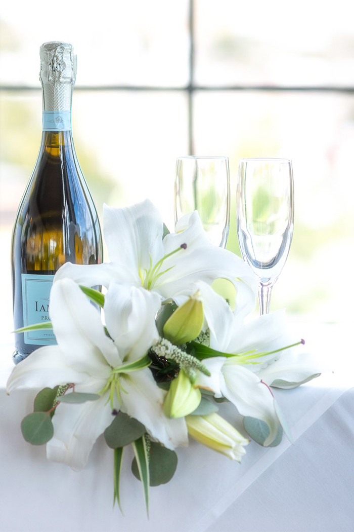 a wedding bouquet with two champagne glasses and a bottle of champagne 