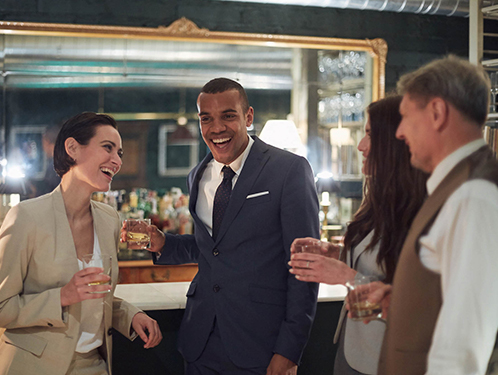 group of people smiling and laughing while standing at a bar