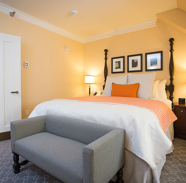 close up view of bed with grey couch and orange accents