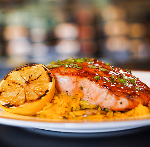 close up image of salmon with rice and a lemon on a plate