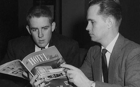 black and white image of two men looking at a magazine 