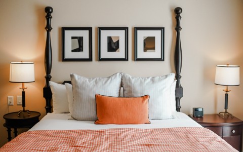 close up of bed with dark bed frame and orange accents 