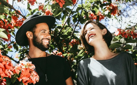 two people smiling and laughing with flowers around them 