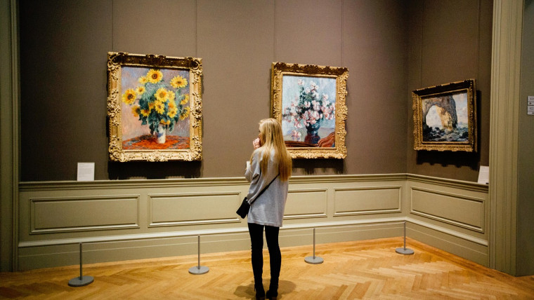 Woman looks at paintings in a museum