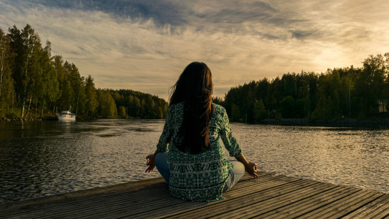 Woman meditating by a lake