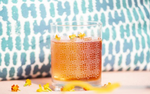 orange cocktail with flowers surrounding 