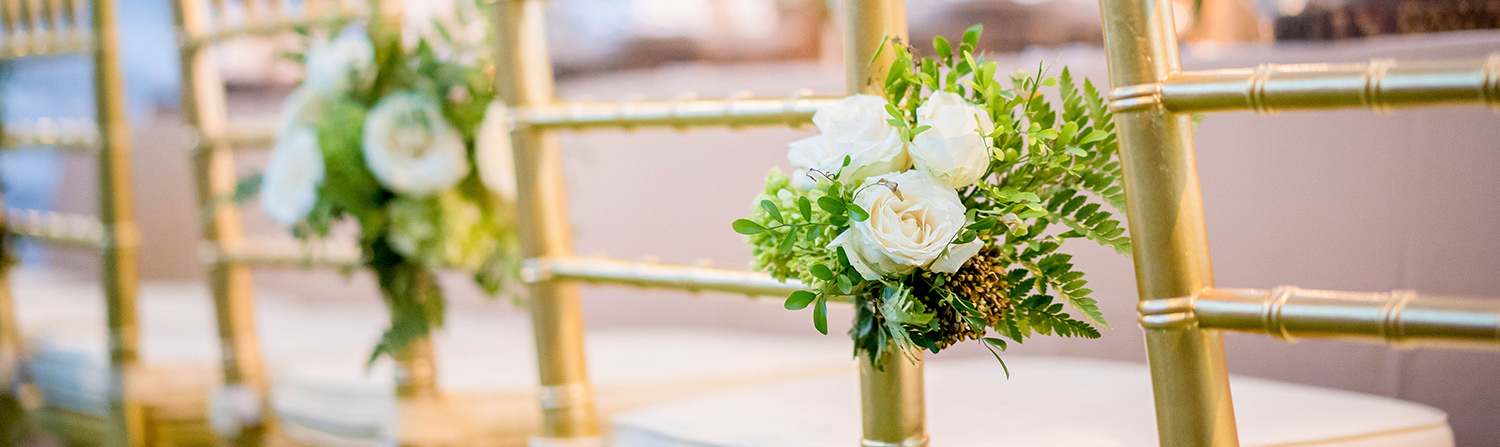 close up shot of gold chairs with corsage on left side