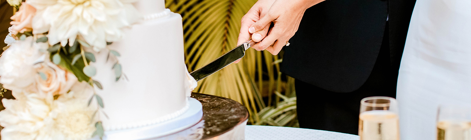 hand cutting wedding cake with knife