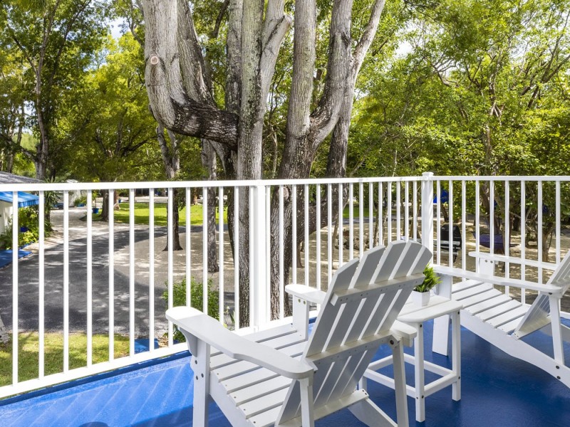 outdoor balcony with white wood chairs with view of large tree