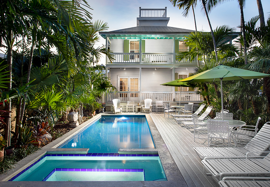 sunset view of a house with a beautiful pool and backyard