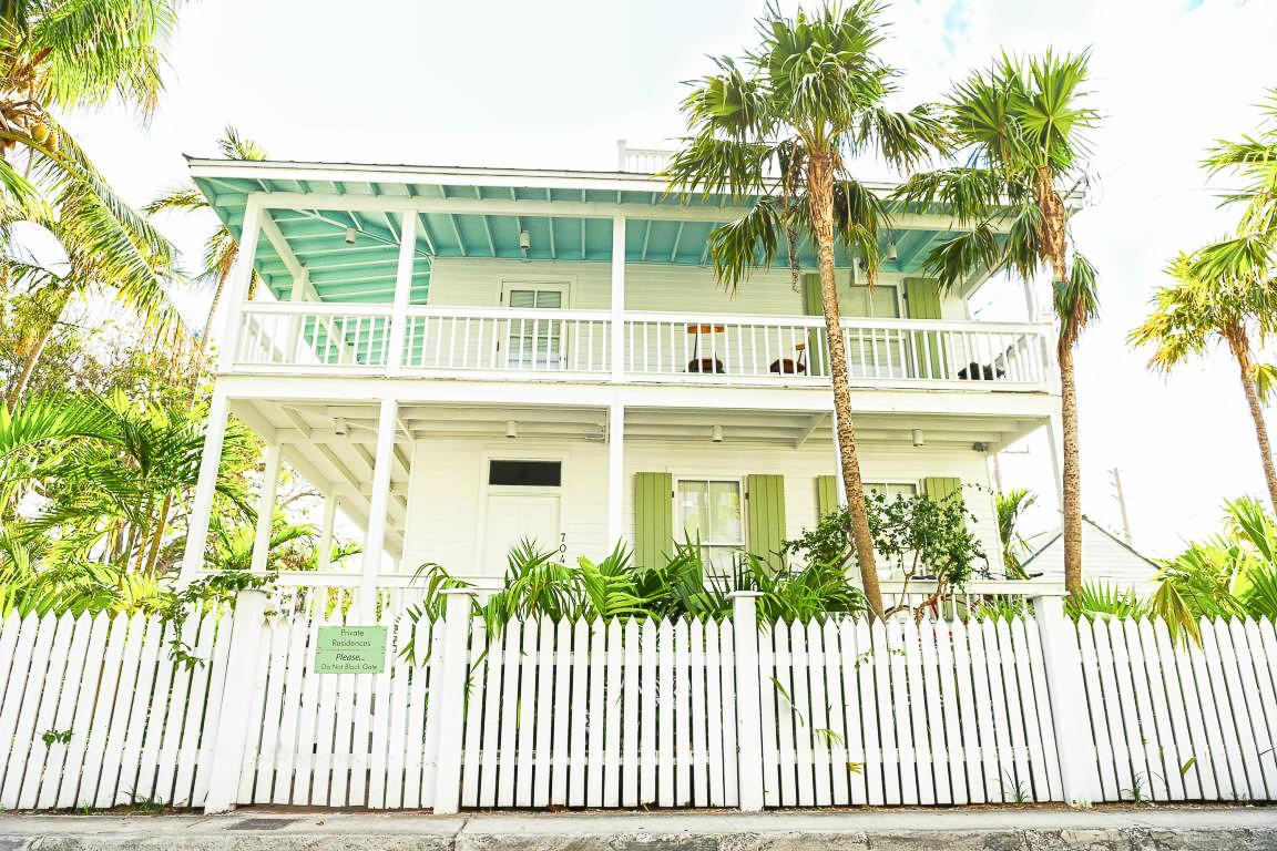 exterior of the main house with palm trees and a white fence outside