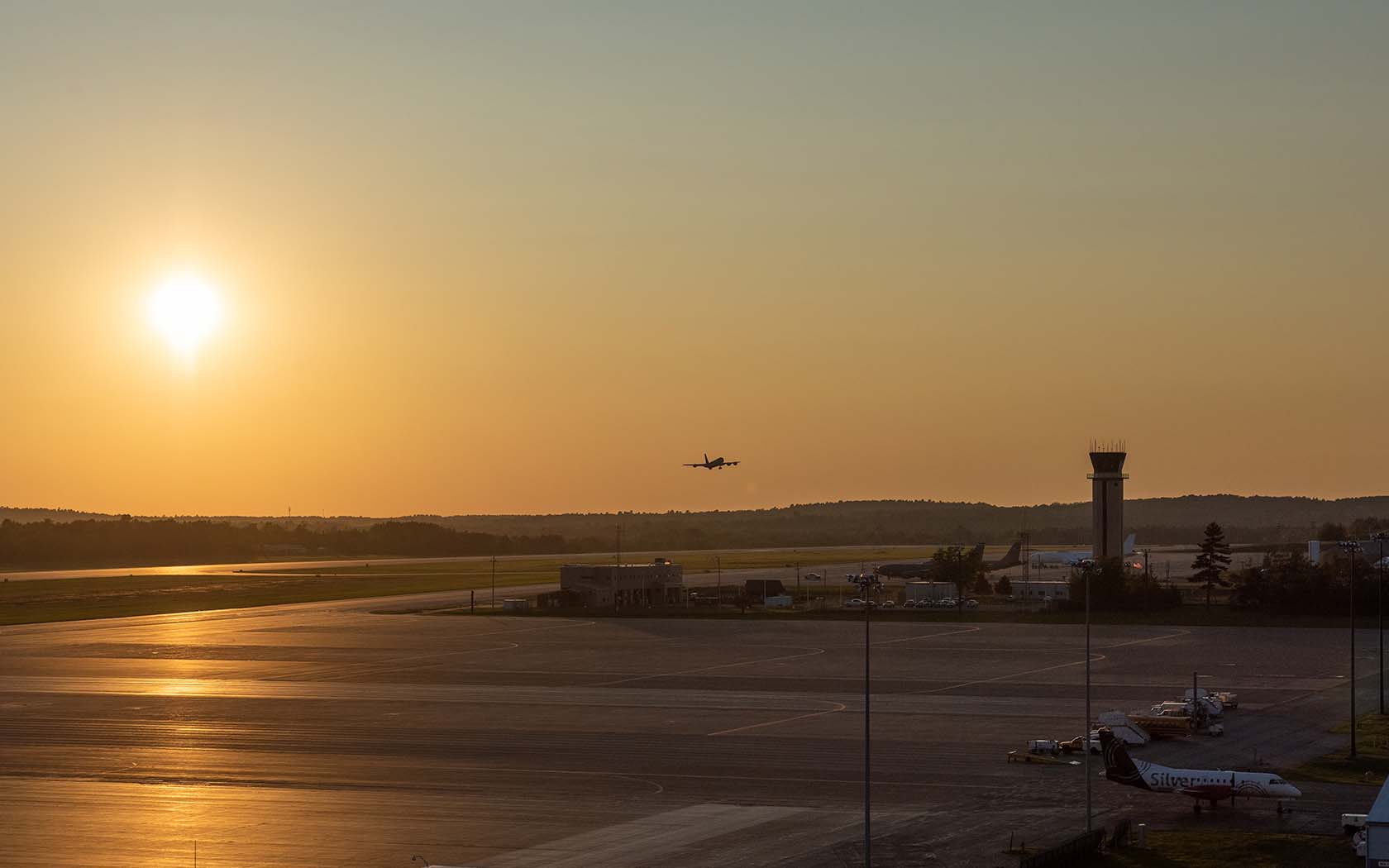 view of airport and sunset with a plane coming in for arrival in background