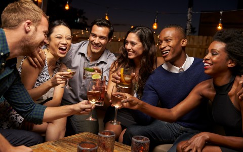 people gathered laughing while they are holding a drink