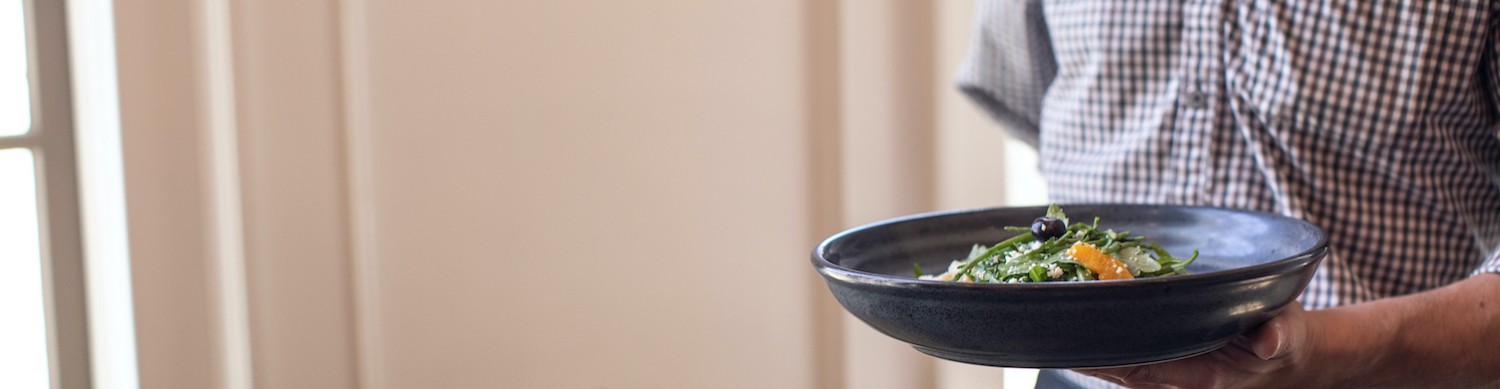 server in plaid shirt holding bowl of fresh greens