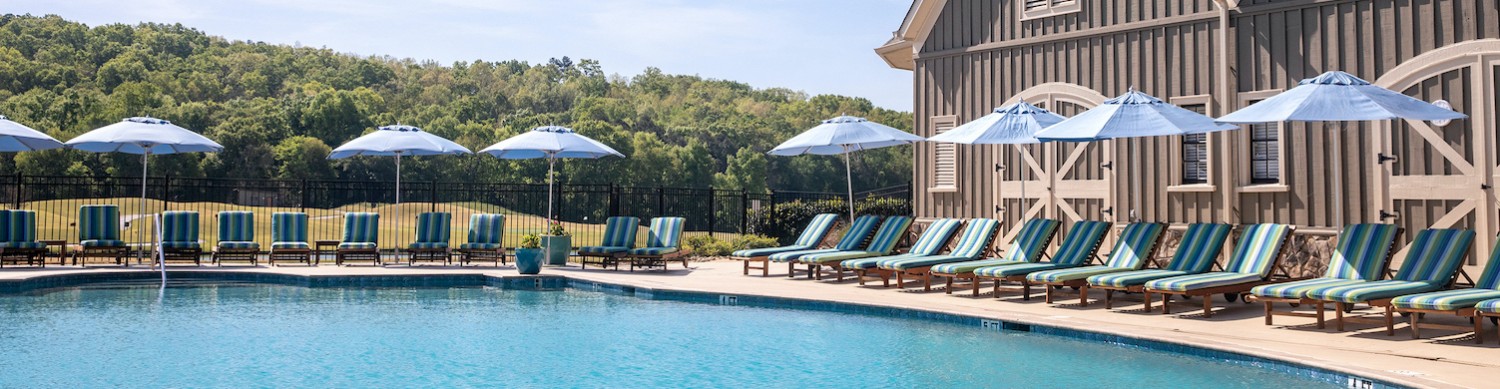 turquoise pool with blue lounge chairs and umbrellas