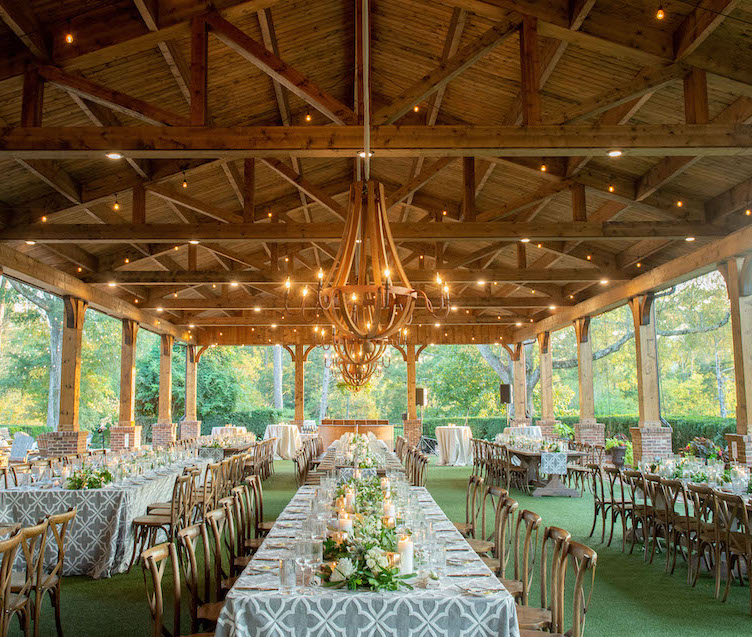 wood pavilion with warm string lights and table settings for wedding