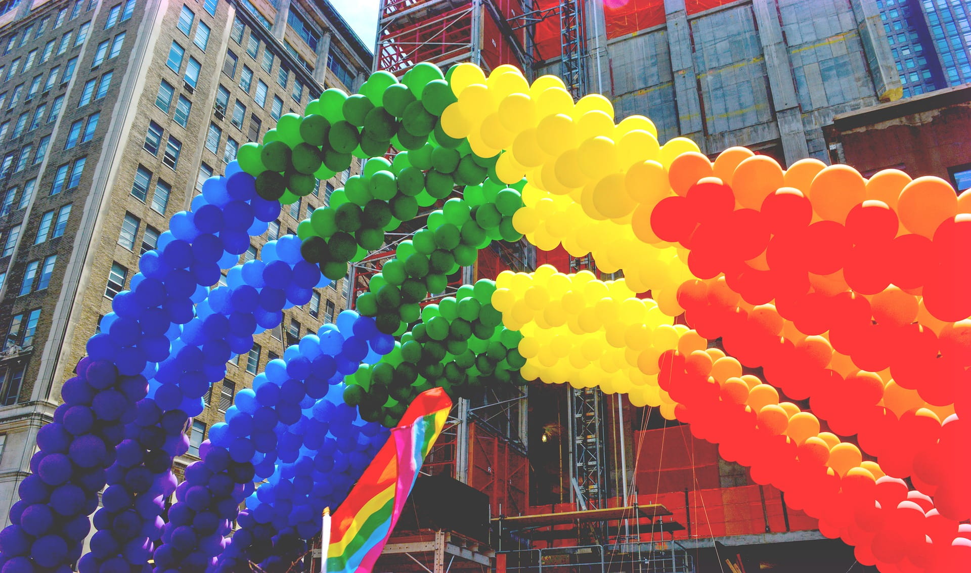 Rainbow pride balloons with tall buildings in background