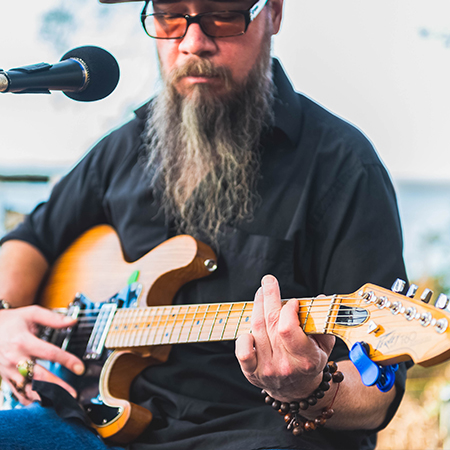 a man with a beard playing a guitar outside