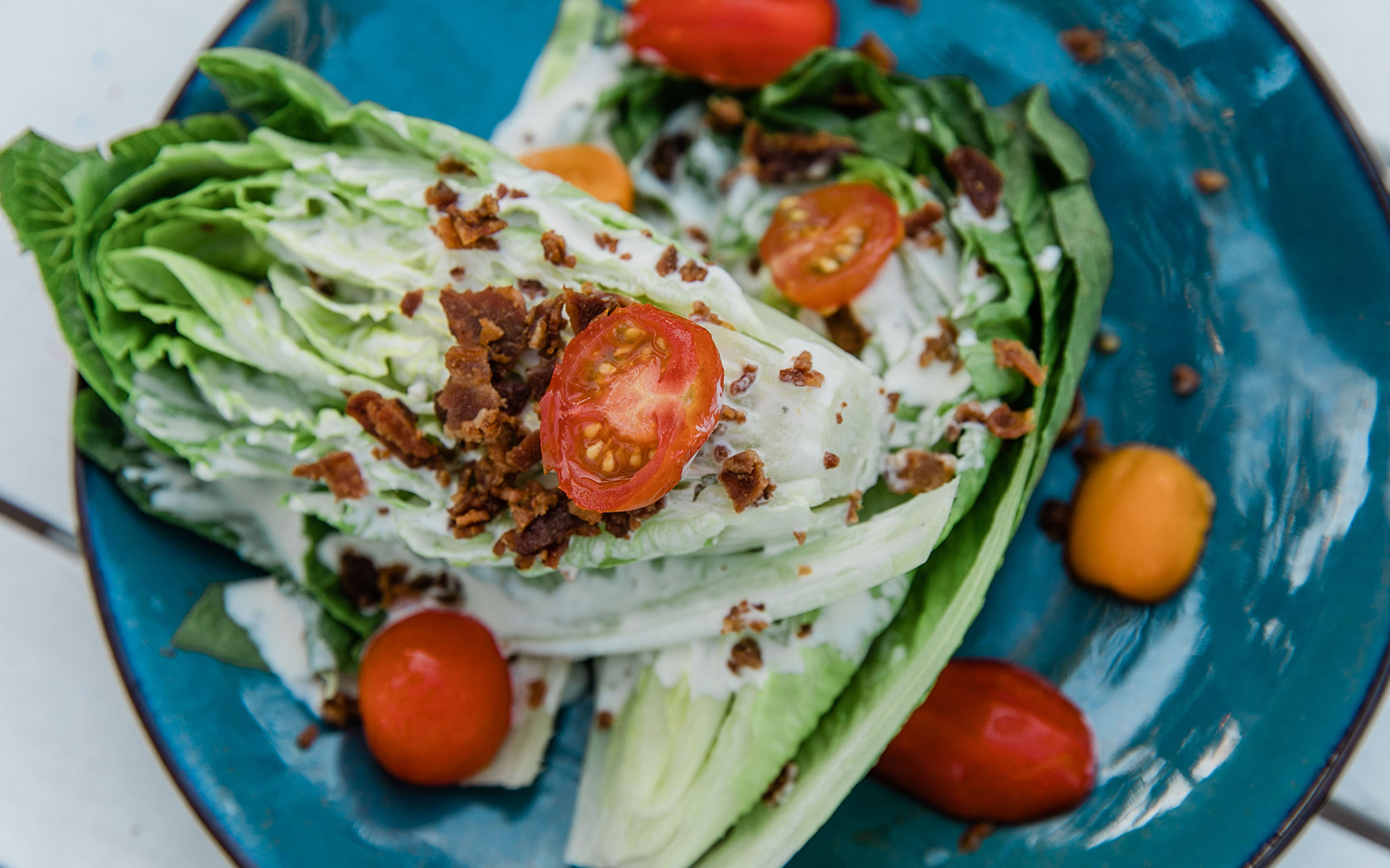 a wedge salad topped with bacon bits and fresh tomatoes