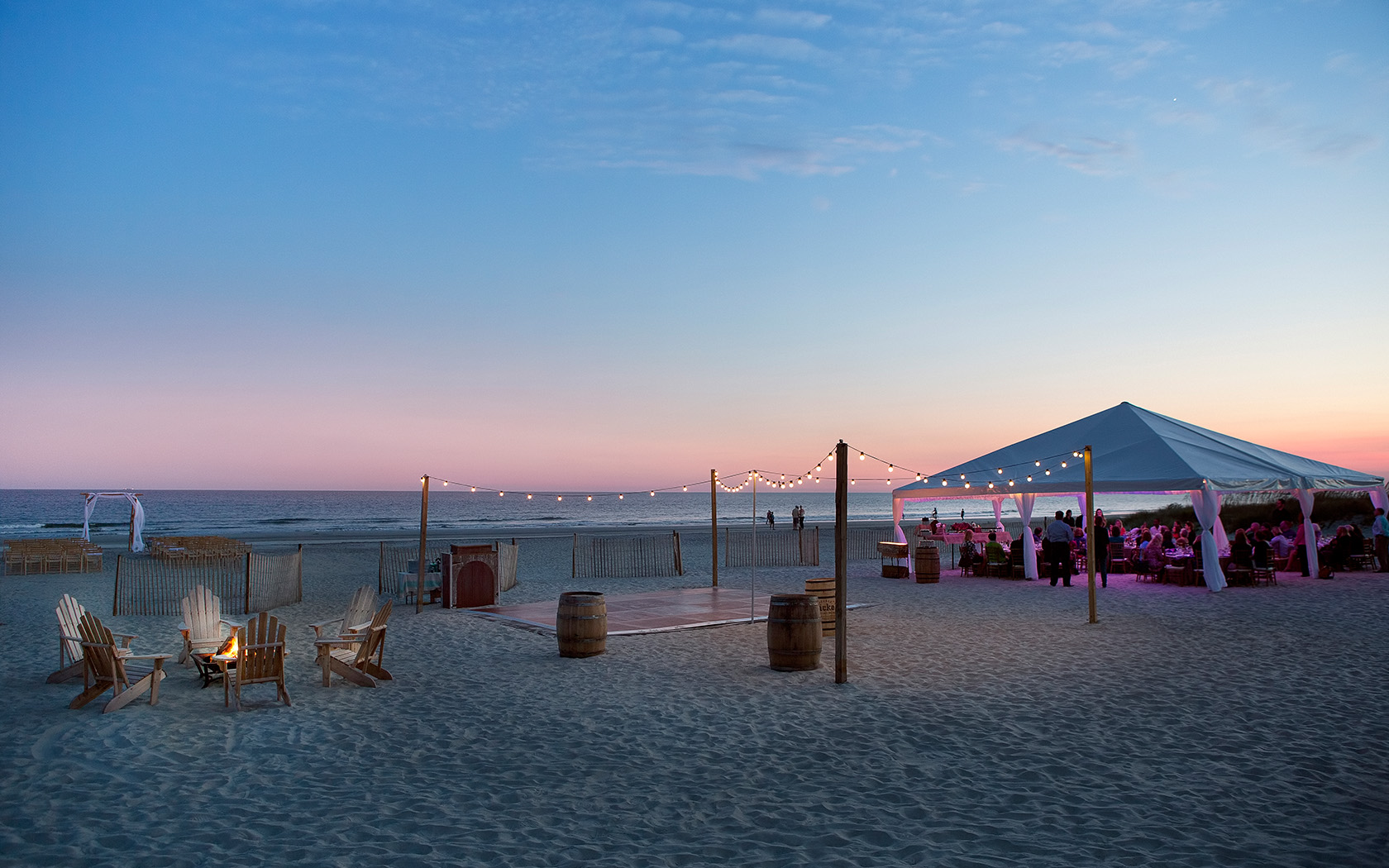 the sun setting and a dance floor that is on the beach
