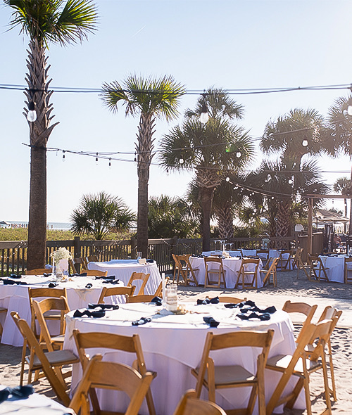 many tables set up for an event outdoors on the sand with the sun shining brightly