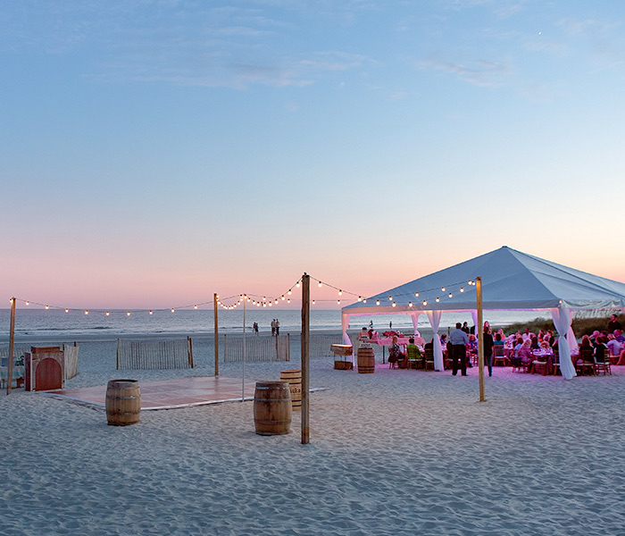 an event on the beach with a dancefloor at dusk